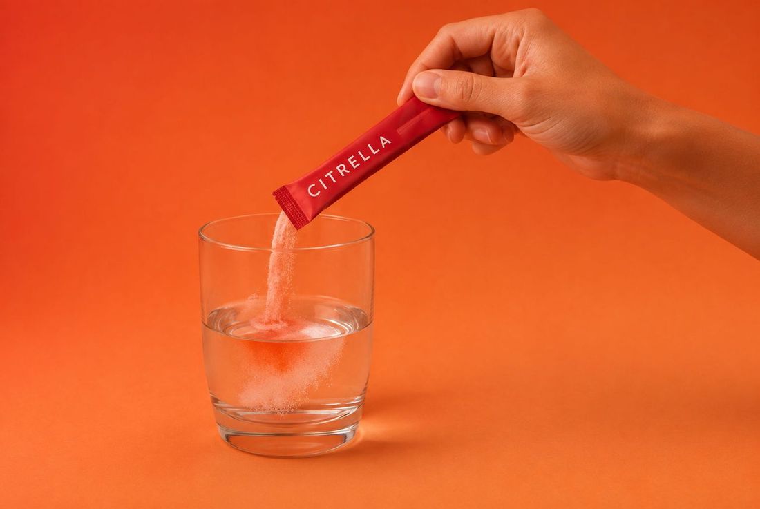 Hand pouring the powder from a Citrella slim stick into a glass of water
